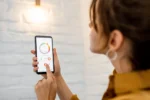 Mulher usando aplicativo de automação residencial no celular para controlar luzes