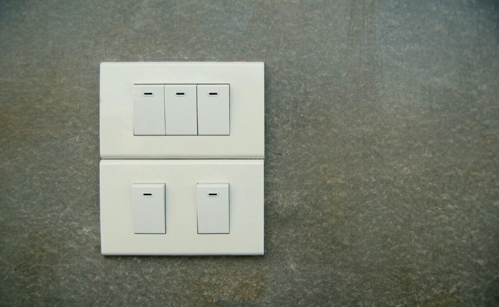Conjunto de interruptores de luz tradicionais de plástico branco instalados em uma parede cinza.