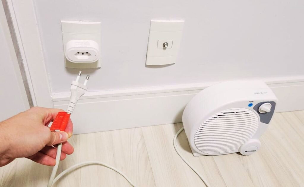 Close-up de uma mão conectando um aquecedor em uma tomada inteligente, solução para controlar o consumo de um aquecedor elétrico que gasta muito.